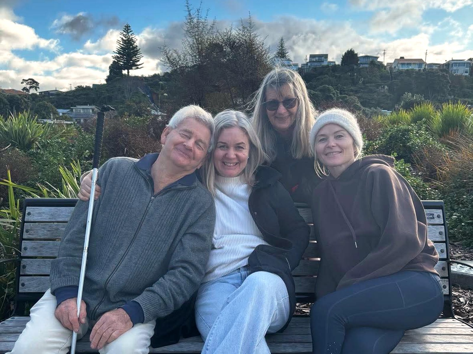 Charlie with her mum, dad and sister on a bench by the coast